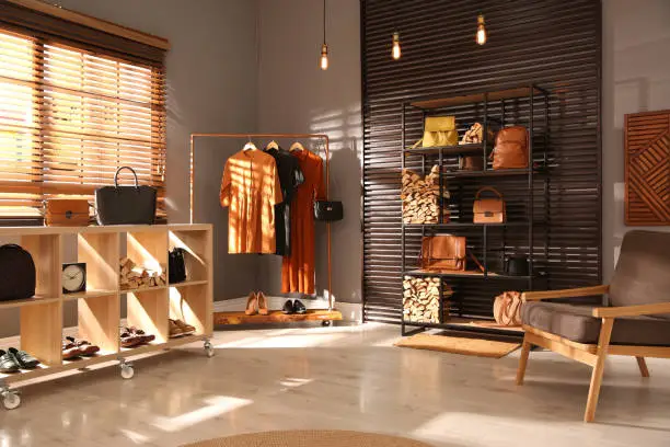 Photo of Collection of stylish woman's bags and clothes in modern boutique
