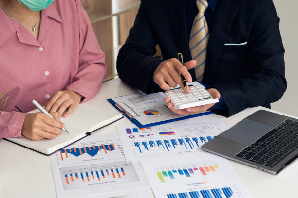 istock Business team discussing and planning projects using charts, holding pens and analytical papers on office table. with a laptop computer and a financial graph running in the background. business idea 1355972320