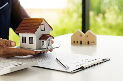 Un agente de bienes raíces ofrece una muestra de hogar seguro de hogar para firmar el acuerdo. con documentos del contrato de compraventa o arrendamiento photo