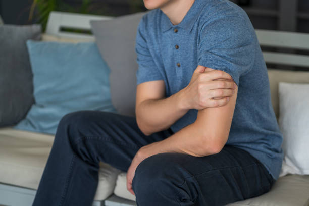 istock Man with pain in shoulder at home 1355972716