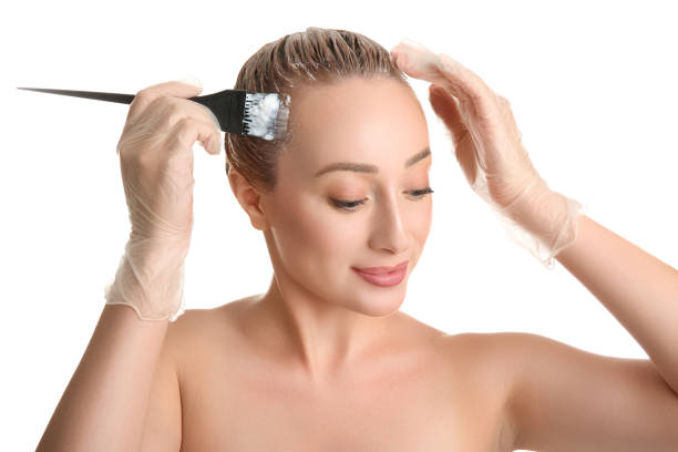 istock Young woman applying dye on hairs against white background 1355974543