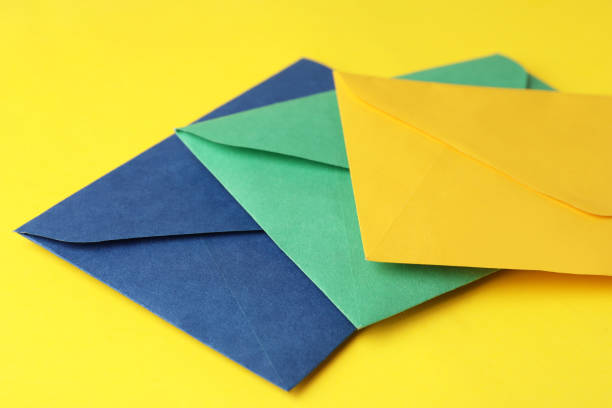 istock Colorful paper envelopes on yellow background, closeup 1355974580