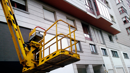 Cherry picker and apartment buildings facades. Lugo province, Galicia, Spain.