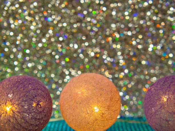 Glowing Christmas cotton balls on a background sparkling with multicolored lights.
