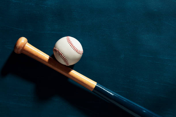 istock Blue wooden baseball bat and a baseball ball on blue background 1355975814