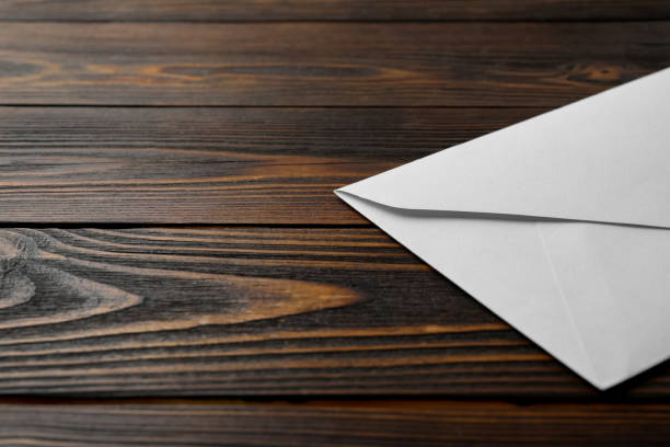 istock White paper envelope on wooden background, closeup. Space for text 1355976933