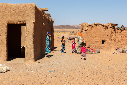 Errachidia Province, Morocco - October 15, 2015: Berber huts in the Sahara Desert. Berber women and children stand outside the house.