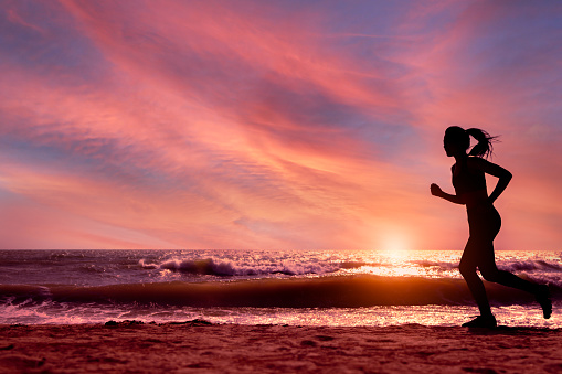 Silhouette female running on beach in sunset or sunrise time