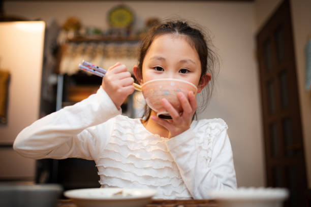 A girl eating rice with chopsticks and a bowl