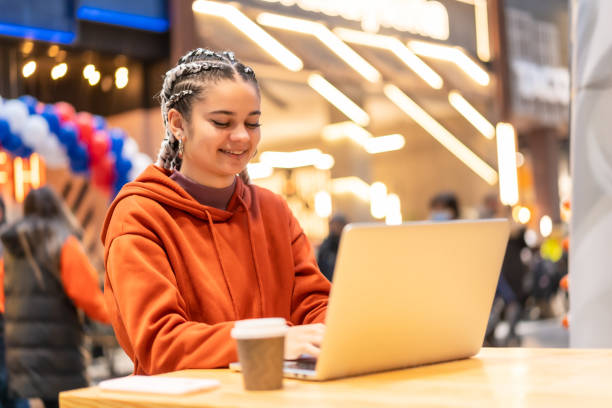 istock Alternative girl with white braids using a computer in a shopping center, sending an email 1355984899