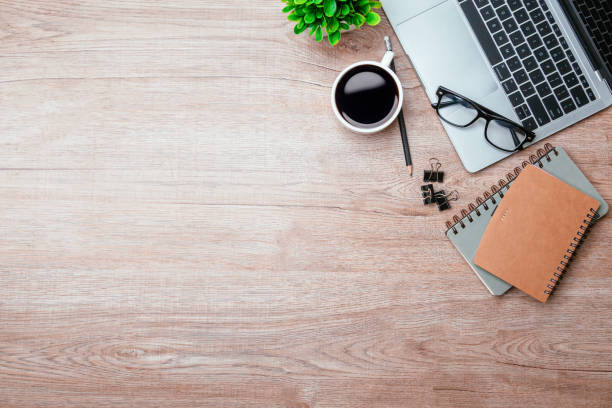 istock Work from home. desk office with laptop, blank notepad, coffee cup and pen on wood table. Flat lay top view copy spce. 1355985096