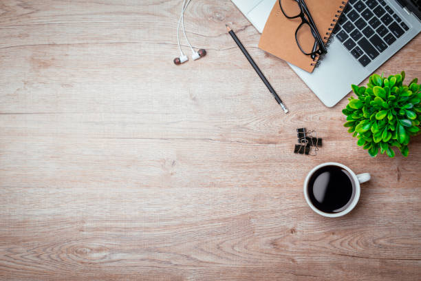 istock Work from home. desk office with laptop, blank notepad, coffee cup and pen on wood table. Flat lay top view copy spce. 1355985100