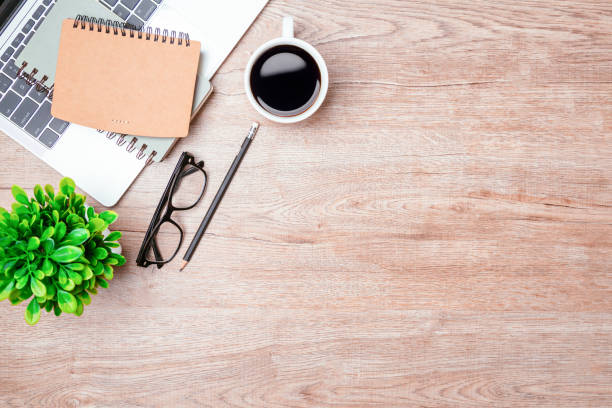 istock Work from home. desk office with laptop, blank notepad, coffee cup and pen on wood table. Flat lay top view copy spce. 1355985105