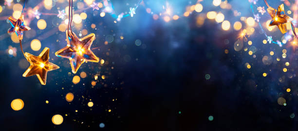 istock Christmas Lights - Golden String Hanging In Blue Background With Abstract Defocused Bokeh 1355985246