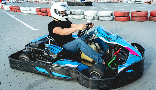 A young man drives a go kart at circuit.
