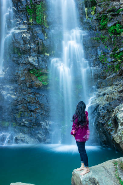 istock young girl watching waterfall falling from mountain with calm blurred water surface at morning 1355992049
