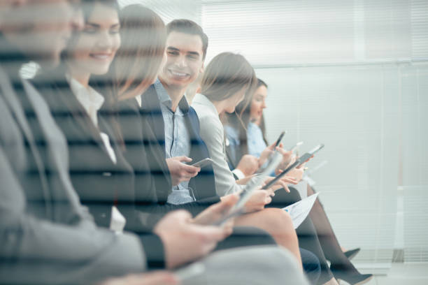group of young candidates with questionnaires sitting in the office corridor stock photo