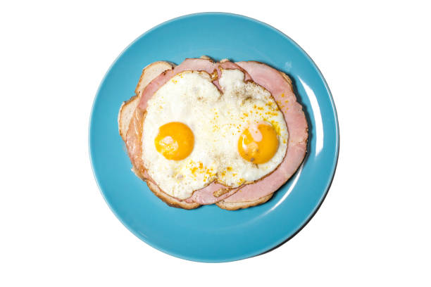 Top view of a meat sandwich with fried egg. Yellow egg yolk.\nDutch lunch Uitsmijter.