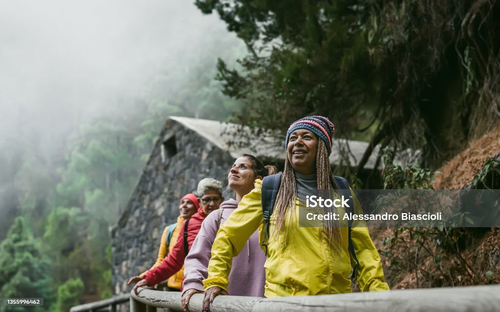 Group of women with different ages and ethnicities having fun walking in foggy forest - Adventure and travel people concept Travel Stock Photo