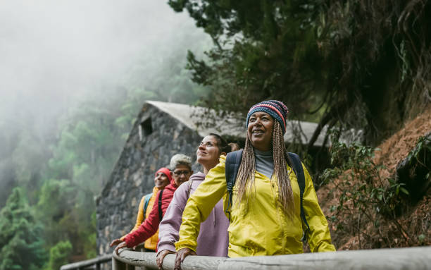 group of women with different ages and ethnicities having fun walking in foggy forest - adventure and travel people concept - senior adult multi ethnic group friendship women imagens e fotografias de stock