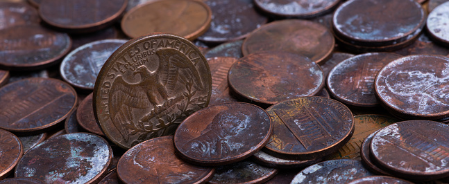 An old 25 American cent coin depicting an eagle on a pile of rusty 1 cent coins