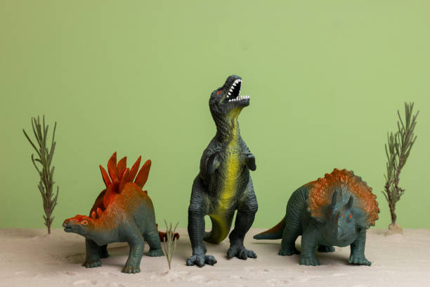 Three toy dinosaurs on a green background.