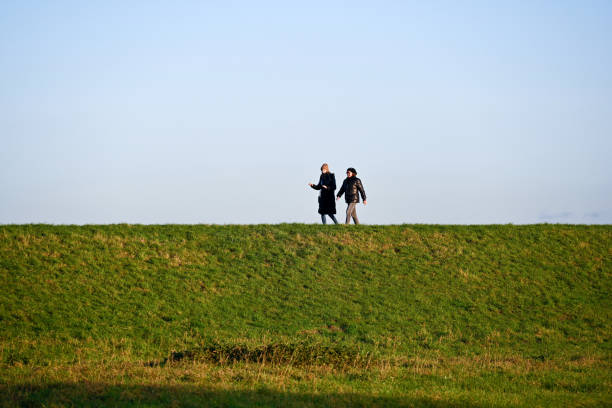 two hiking friends in nature exploring the woodland on a summer day with their dog.