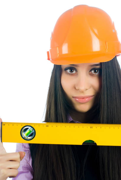 istock Attractive girl in helmet with level tool over white 1355999142