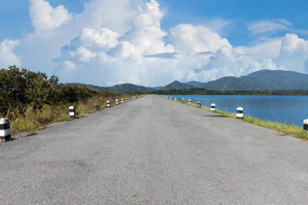 istock Driving on an empty road. Empty asphalt road through the green field and clouds on blue sky in summer day. Open road ahead, endless road for concept. 1356001538
