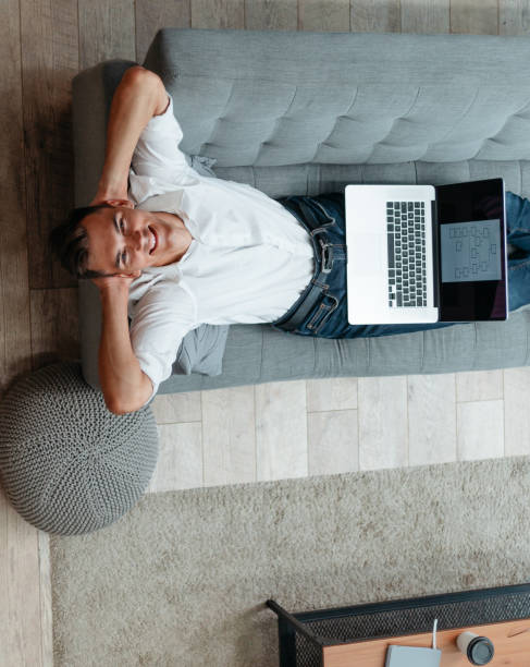 istock young man with a laptop is resting on the couch 1356001746