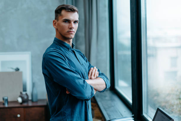 istock confident young man standing near the window 1356001971