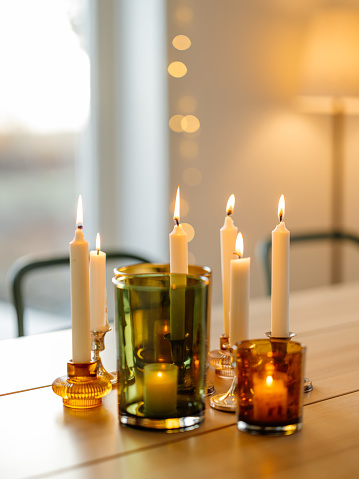 Four candles on wooden stands, three are lit for the third Advent, pine branch decoration, light wooden board and rustic plaster background, copy space, selected focus, narrow depth of field