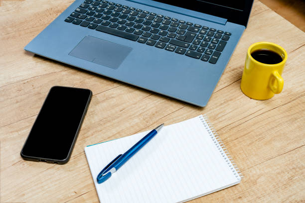 istock Laptop next to a blank notepad, pen and cell phone on a work table with coffee. Technology, communications, homeoffice concept 1356005168