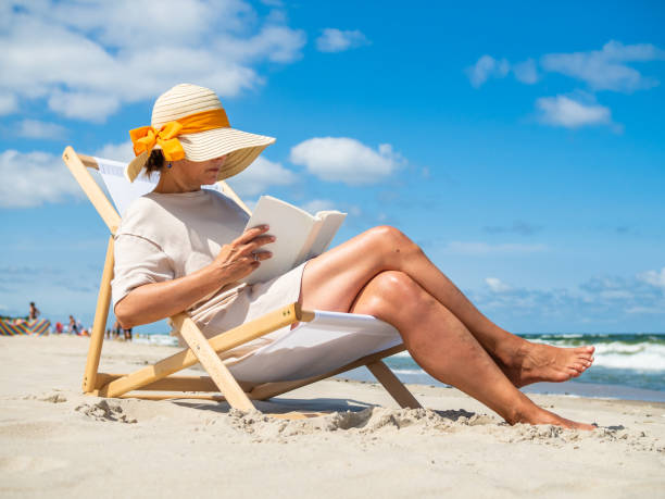 istock Woman relaxing on beach reading book 1356005990