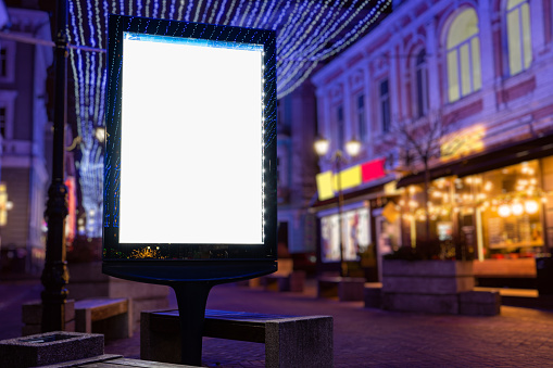Blank white mock up vertical billboard street poster on a christmas illumination city background