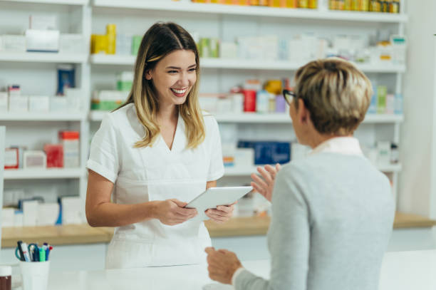 farmaceutka sprzedająca leki w aptece starszej klientce - pharmacist mature adult smiling senior adult zdjęcia i obrazy z banku zdjęć