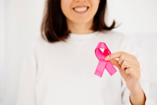 Woman hand holding pink ribbon breast cancer awareness stock photo