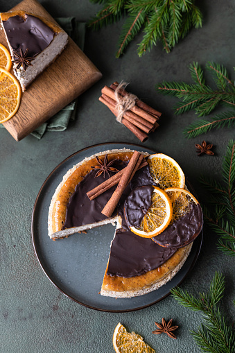 Cheesecake with chocolate decorated slices of dried oranges, cinnamon and anise. Festive Christmas or New Year decoration. Top view. Selective focus.