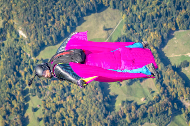 un homme en wingsuit glisse dans un ciel dégagé - wingsuit photos et images de collection