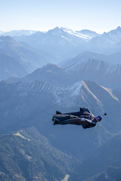 istock Man in wingsuit glides, upside down, over scene 1356014317