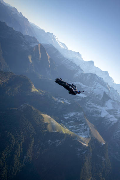 istock Man in wingsuit glides, upside down, over scene 1356014343