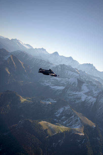 istock Man in wingsuit glides, upside down, over scene 1356014350
