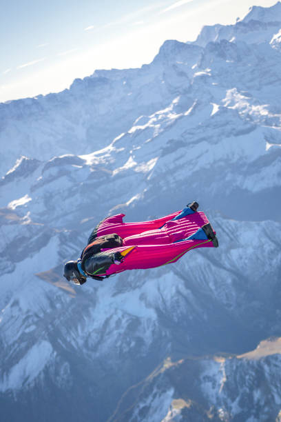 un homme en wingsuit glisse dans un ciel dégagé - wingsuit photos et images de collection