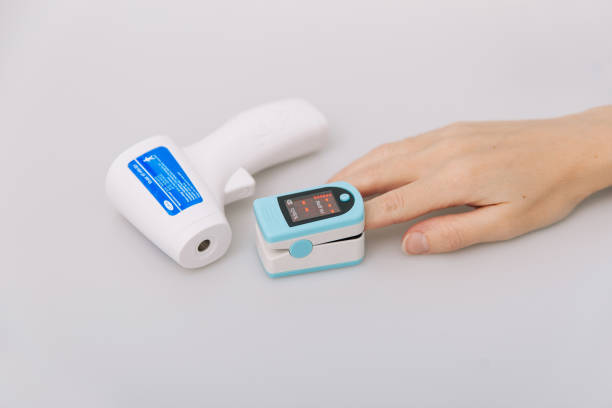 istock Pulse oximeter and thermometer gun on white background. Measuring oxygen saturation, pulse rate and oxygen levels. Infrared isometric thermometer gun to check body temperature for virus symptoms 1356016608