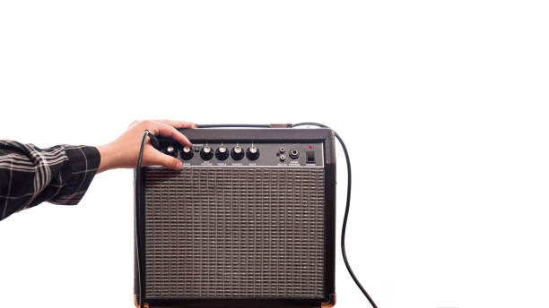 hand adjusts the gain on an amplifier connected to the power on white background. - baffle imagens e fotografias de stock