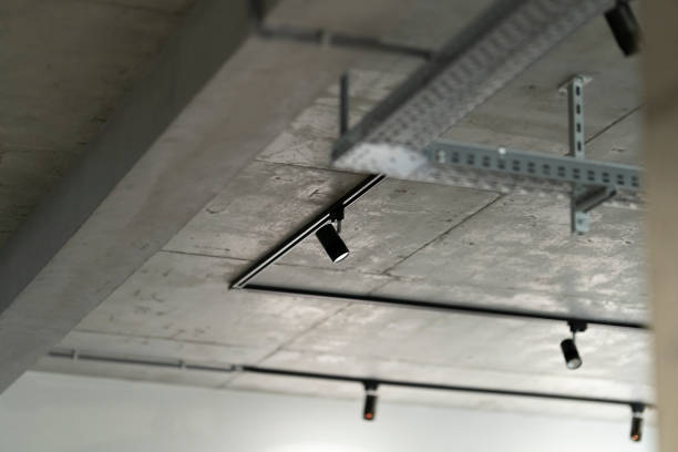 Interior Moder Loft interior style fragment. Black track lights on a concrete ceiling. Led track spotlights and corrugated wiring on the ceiling. recessed light stock pictures, royalty-free photos & images