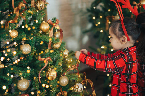 istock Girl in pajamas hangs bauble on Christmas tree 1356018169
