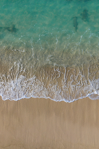 Aerial abstract drone pain of view of an idyllic white sand beach facing turquoise waters of a lagoon in Bali Indonesia.