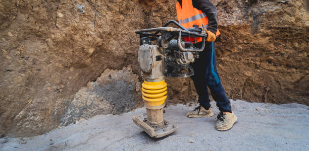 trabalhador usa um rammer de vibração portátil na construção de uma subestação de transmissão de energia - heavy labor - fotografias e filmes do acervo