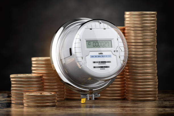 Electric meter and coin stacks. Growth of electricity consumption, price and energy costs concept. stock photo